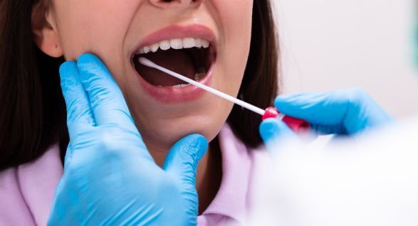 Dentist or healthcare professional performing a salivary test using a swab inside a patient's mouth
